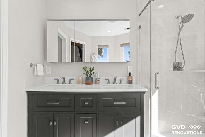 Charcoal double vanity with a quartz countertop and a frameless glass neo-angle shower