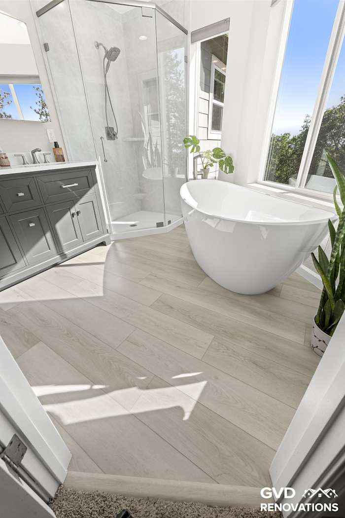 Entry to the marble-look walk-in shower with wood-look flooring