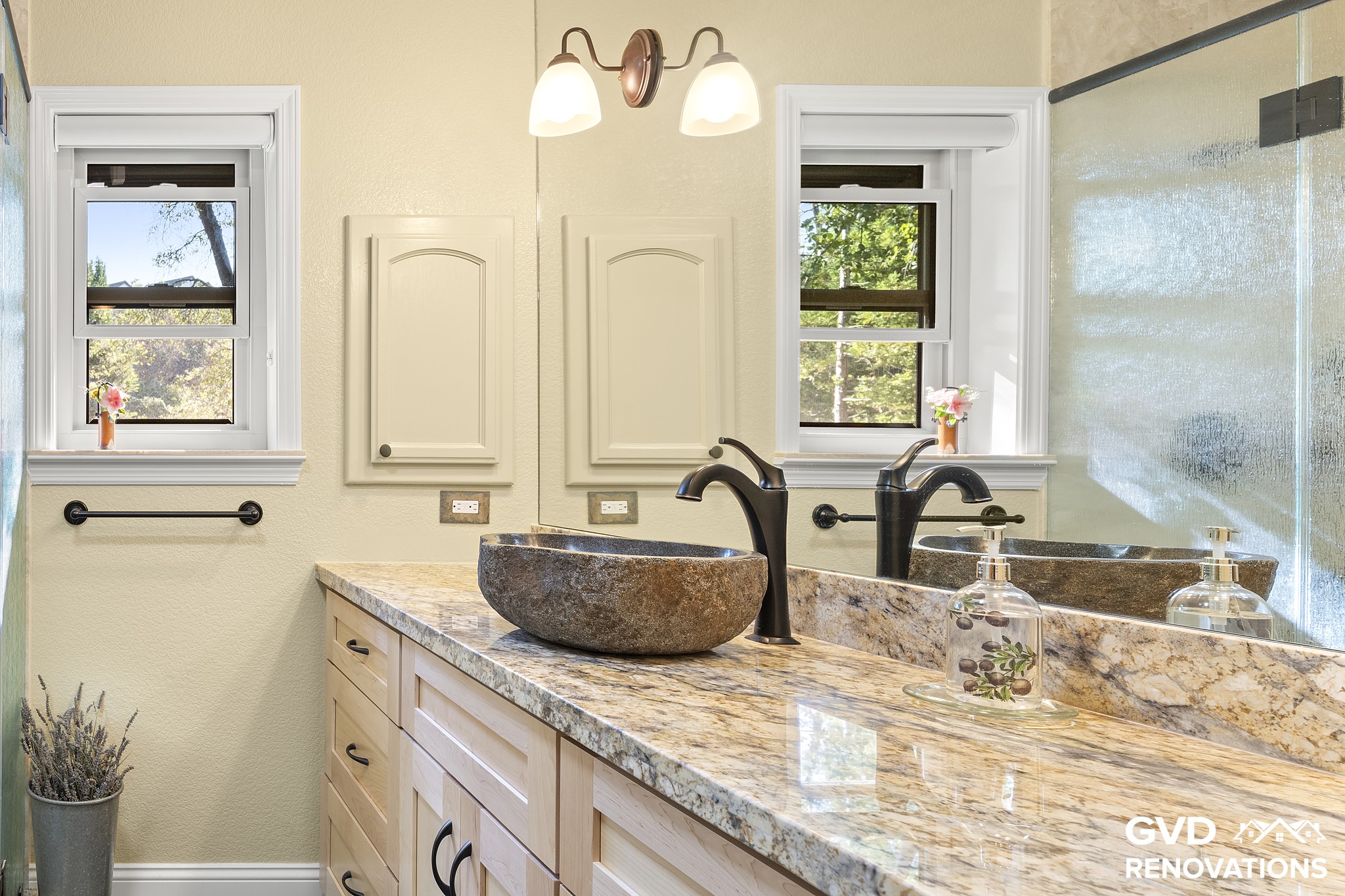 Guest bath maple vanity with a granite countertop, a stone vessel sink and matte-black fixtures beneath a window