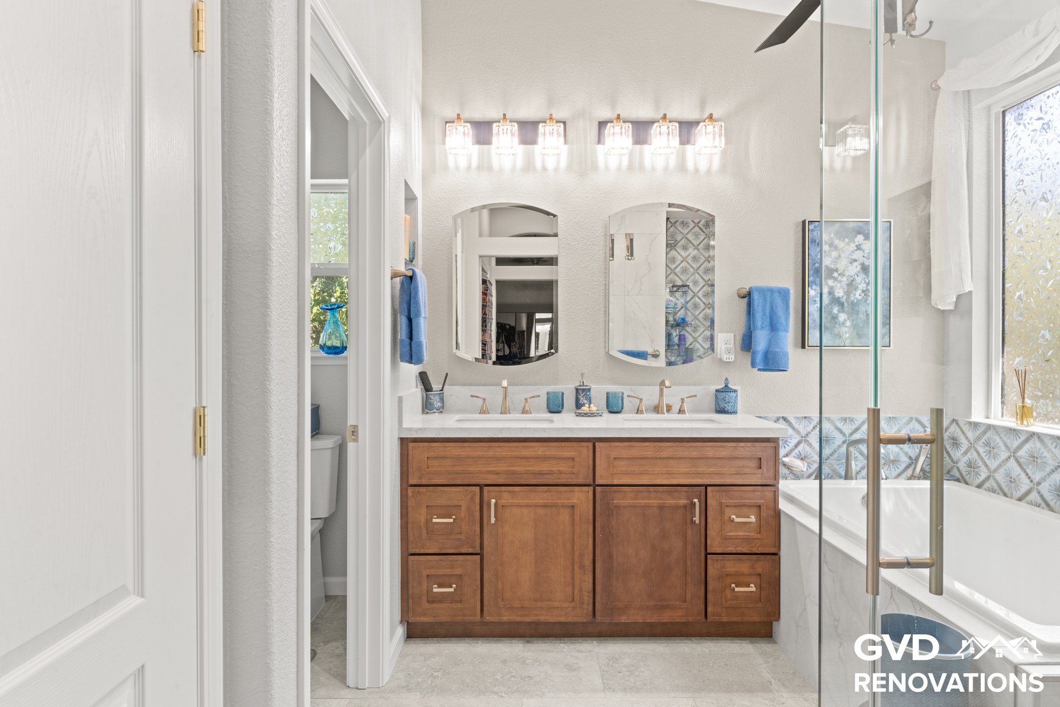 Wood vanity with a quartz countertop beside a frameless glass shower