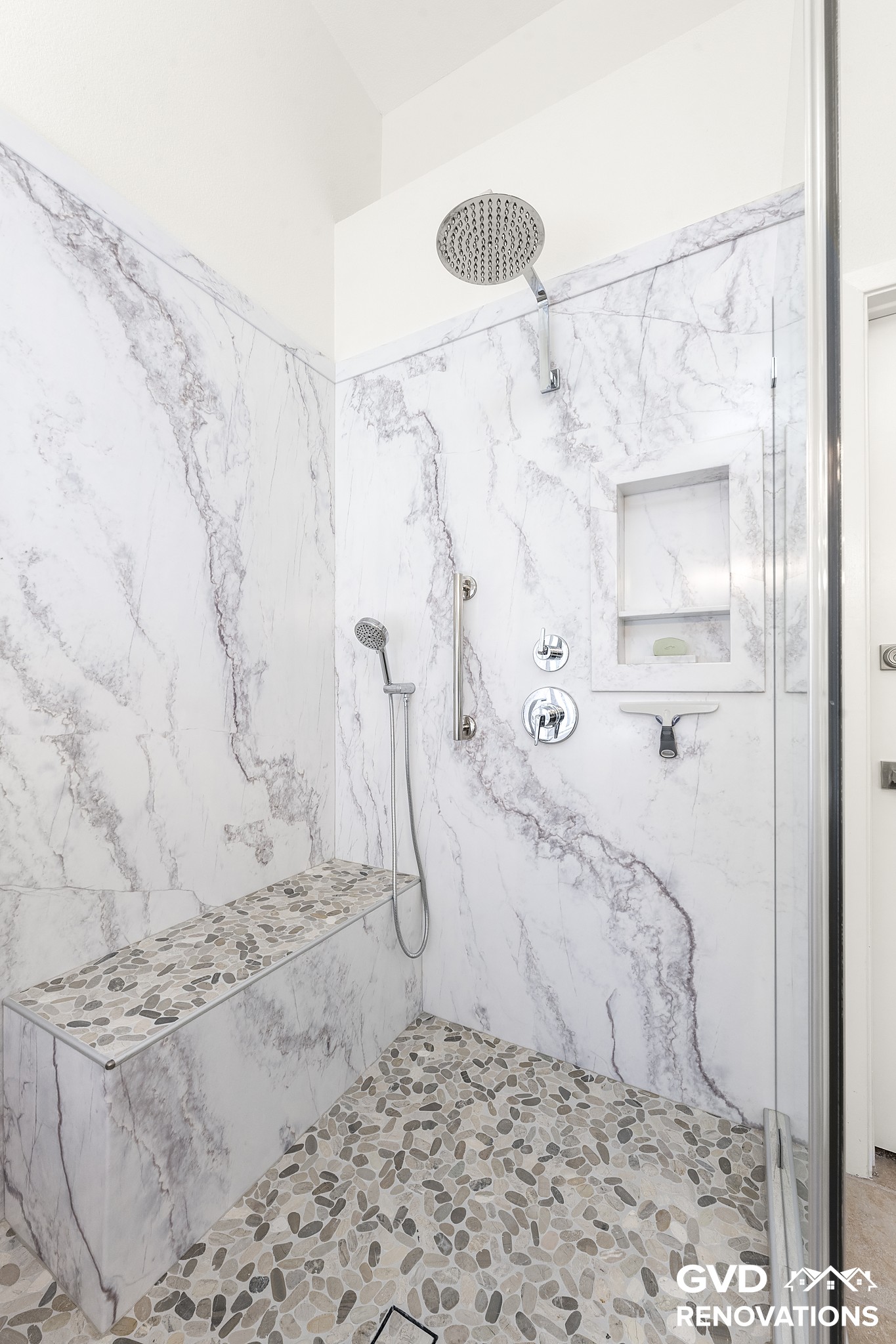 Rainfall shower head and handheld sprayer on large-format marble-look shower walls