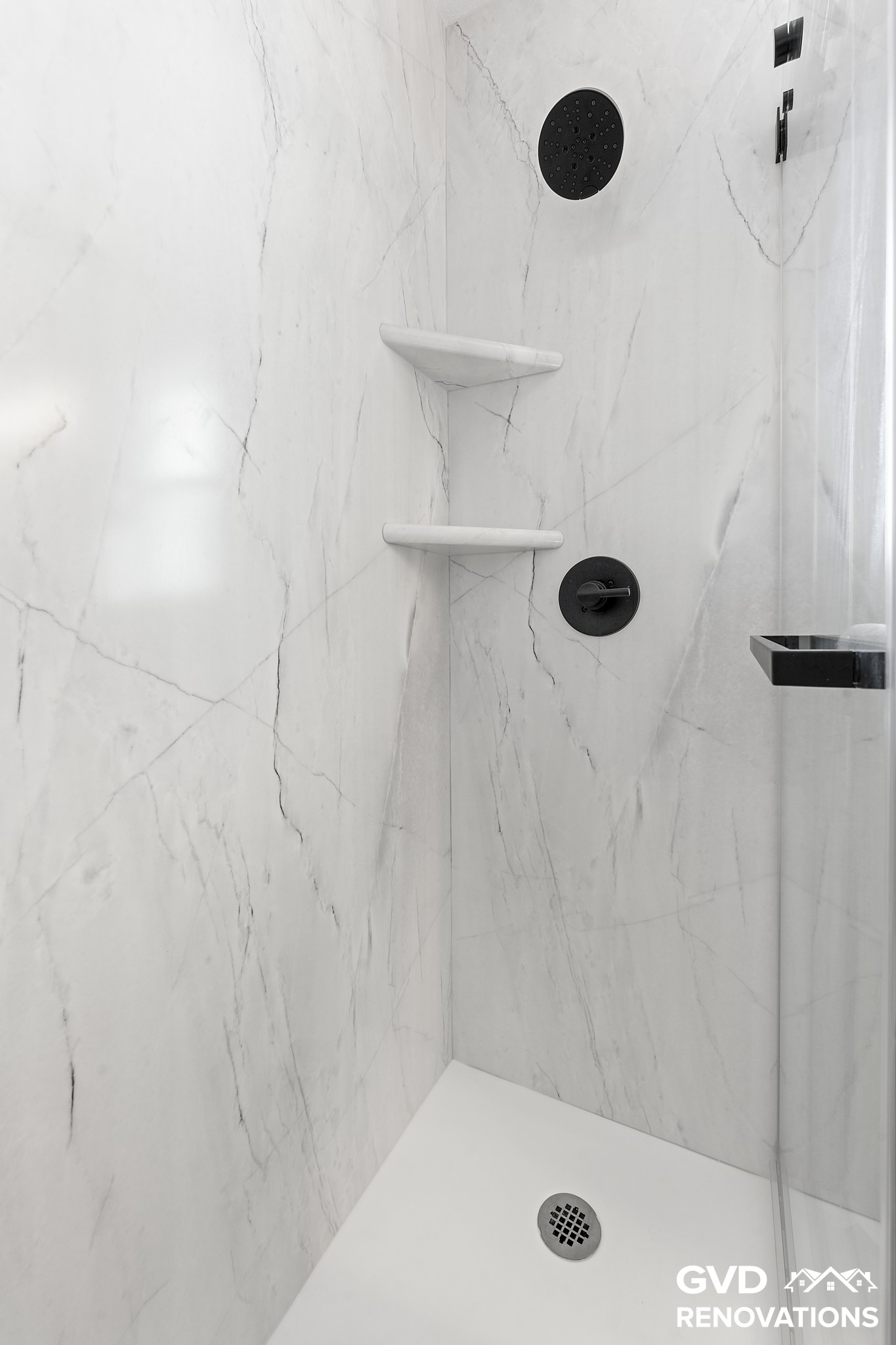 Marble-look shower interior with a recessed niche and a corner shelf