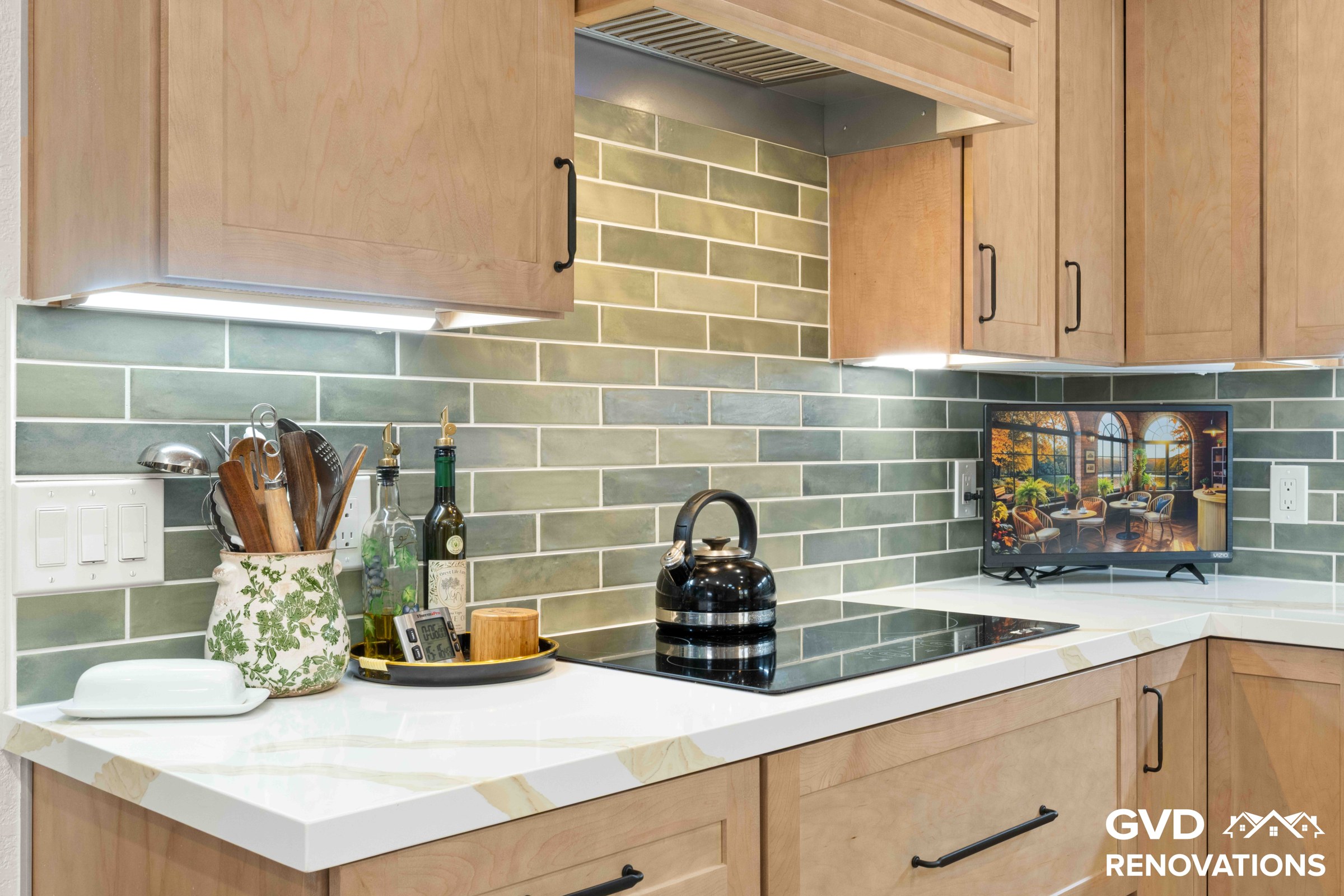 Maple cabinet counter with green subway tile backsplash, under-cabinet lighting and a Calacatta quartz surface