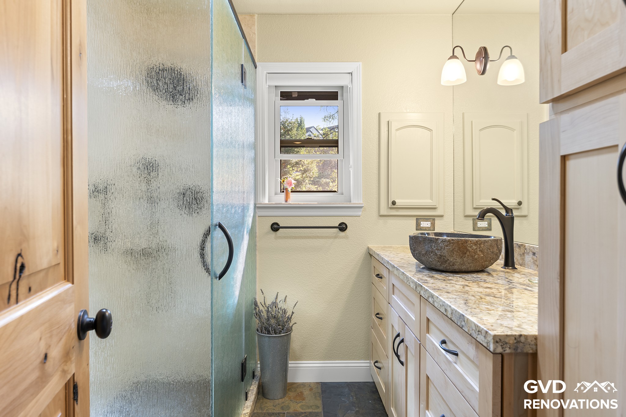 Remodeled guest bathroom in El Dorado Hills with a maple vanity, a stone vessel sink and a glass walk-in shower with slate flooring