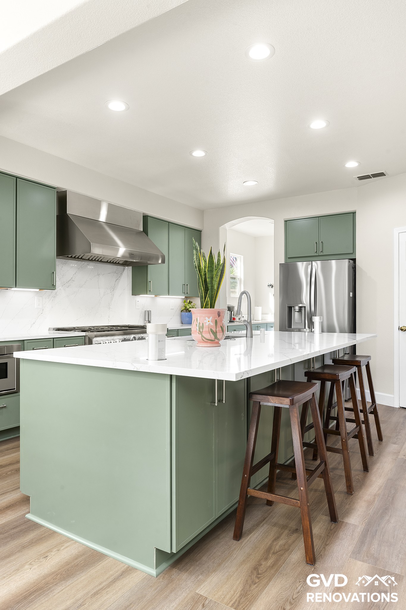 Kitchen island with counter stools facing the range wall and custom hood