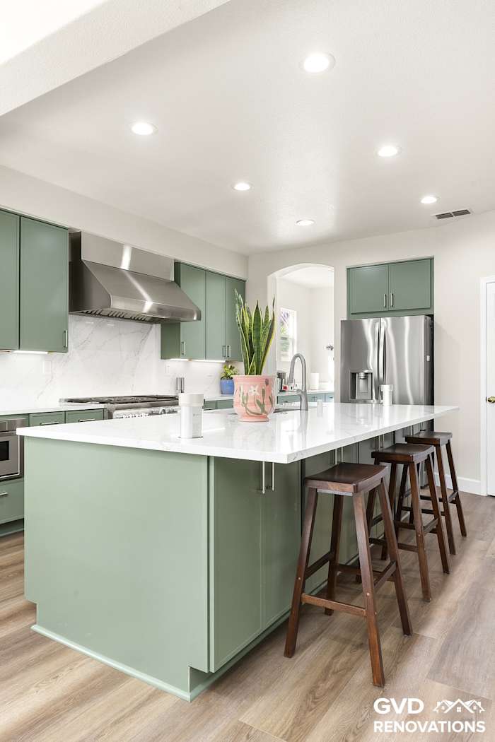 Kitchen island with counter stools facing the range wall and custom hood