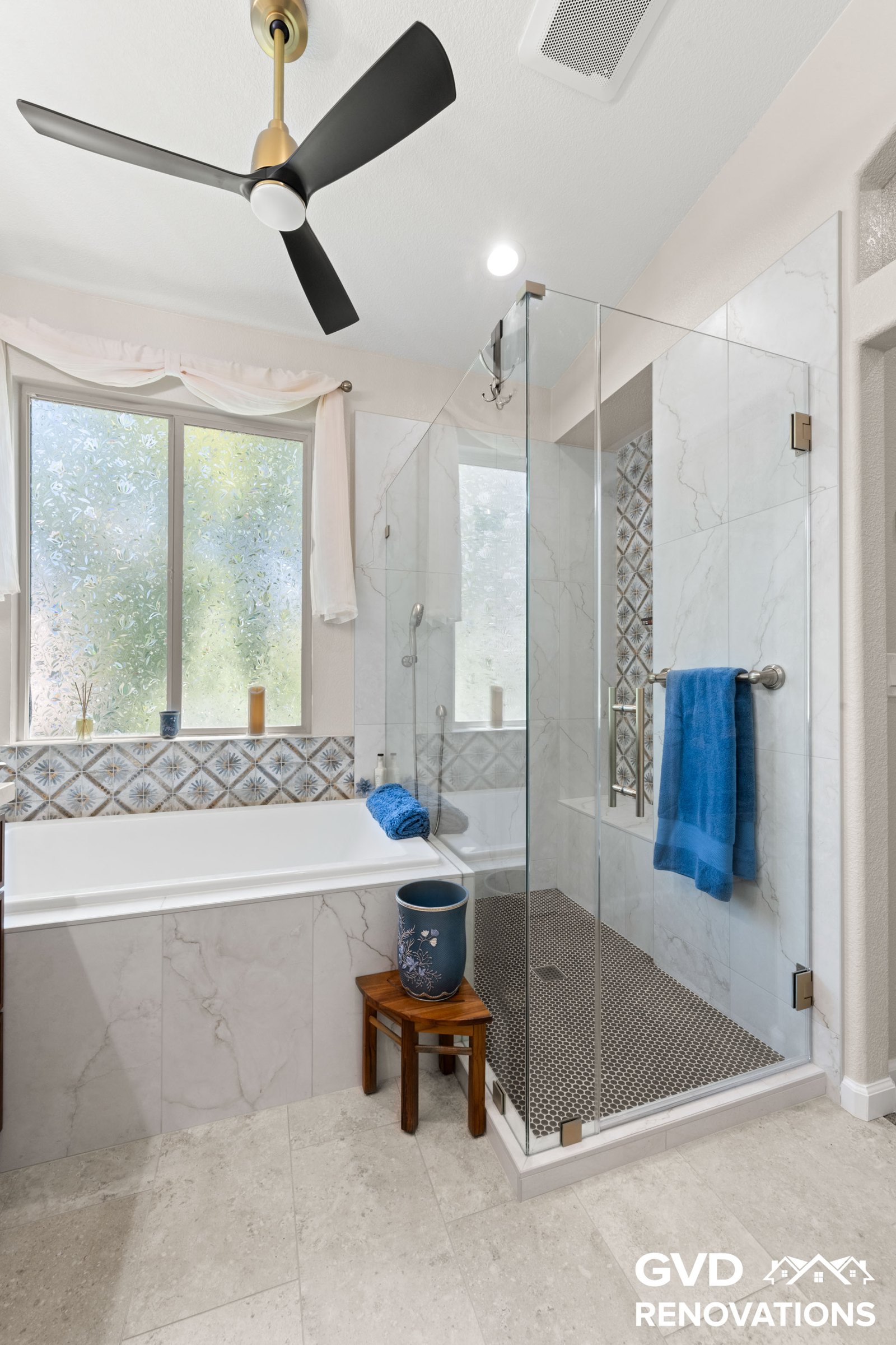 Soaking tub beside a frameless glass shower with a tiled bench
