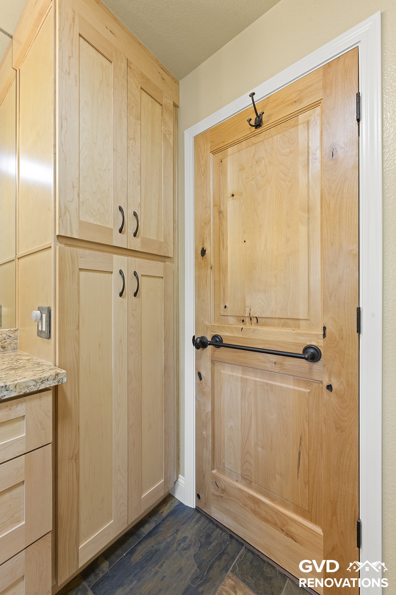 Floor-to-ceiling maple linen cabinet beside a knotty alder pocket door