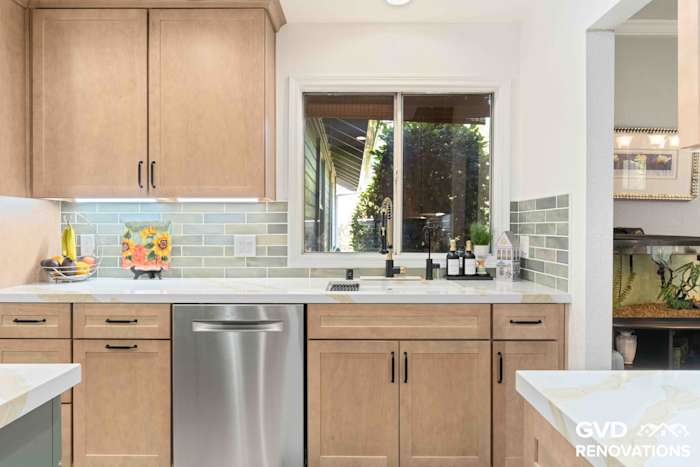 Maple Shaker cabinets with a stainless steel dishwasher, quartz countertops and a window above the counter
