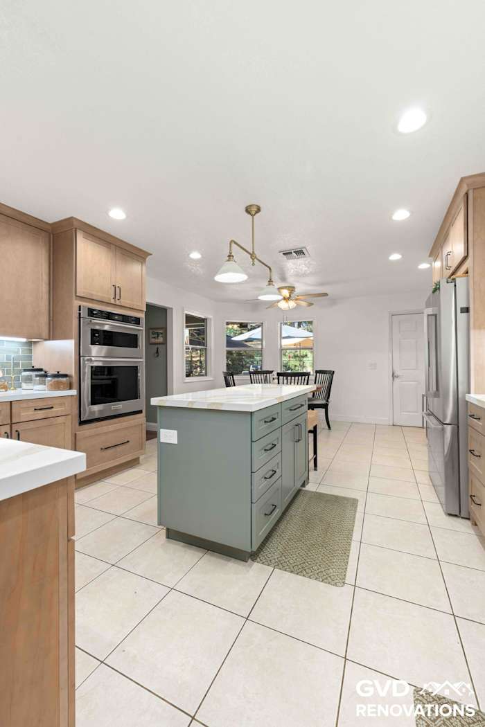 Long view down the remodeled kitchen toward the breakfast nook with the island and pendant lighting