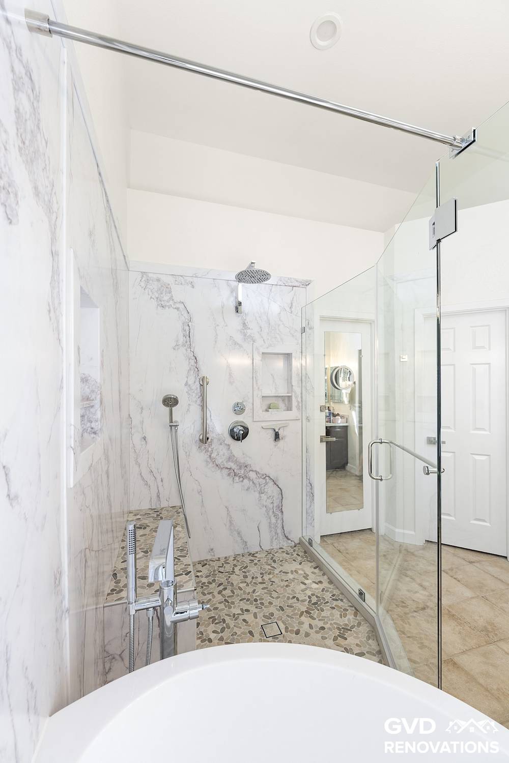 Frameless glass enclosure wrapping the walk-in shower and freestanding tub wet room