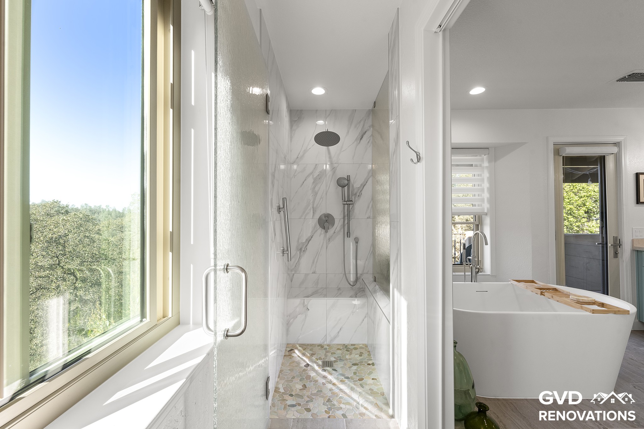 Walk-in shower with marble-look walls, a frameless glass enclosure and a forest-view window