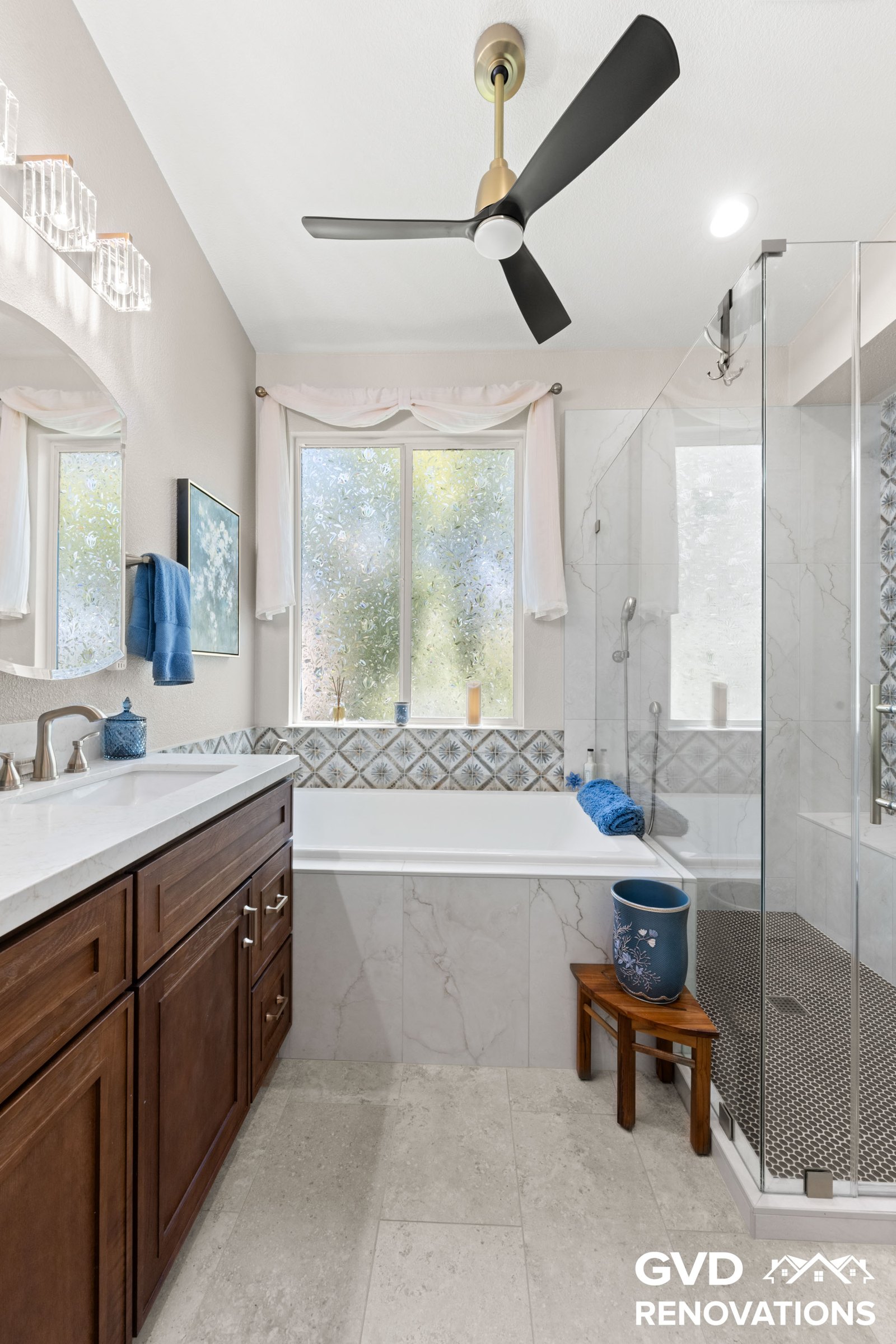 Drop-in tub and vanity with marble tile and a blue mosaic accent detail