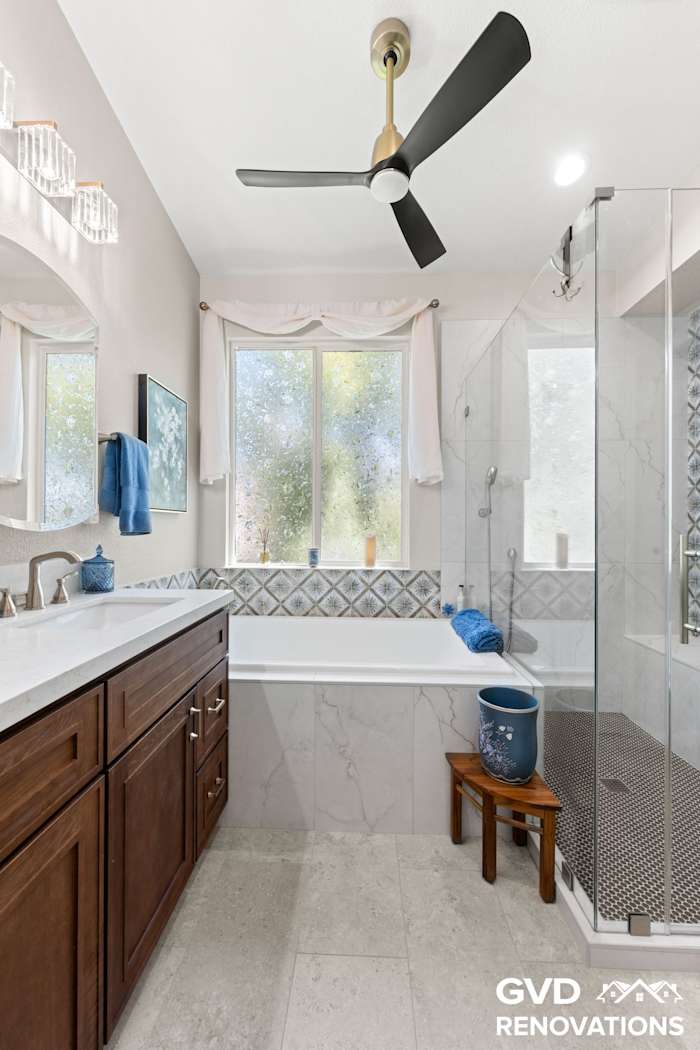 Drop-in tub and vanity with marble tile and a blue mosaic accent detail