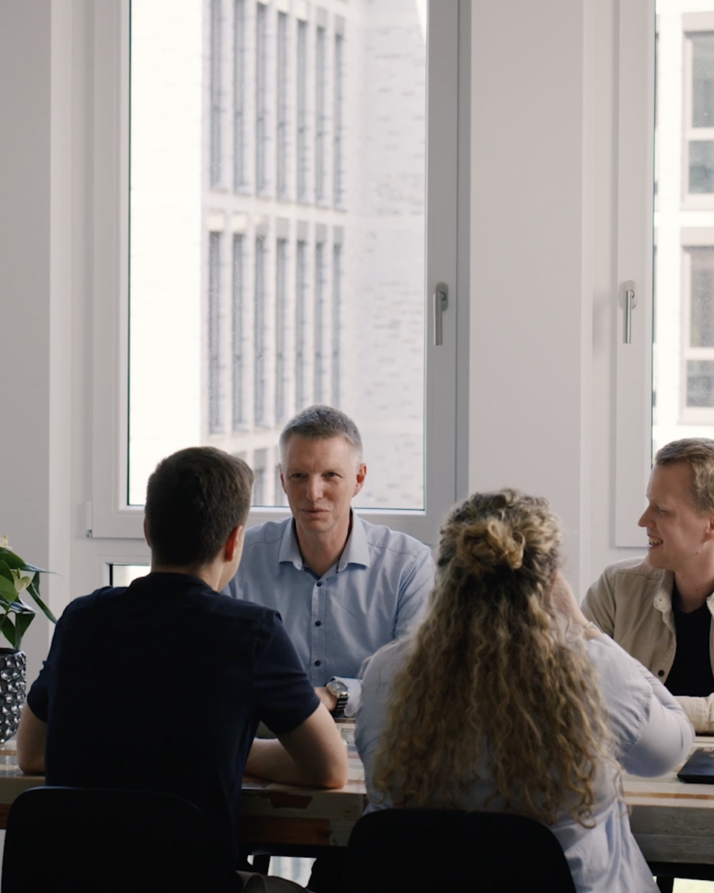 Vier Menschen sitzen sich gegenüber an einem Tisch und reden