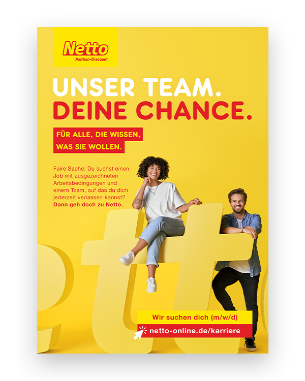 Auf einem gelben Hintergrund steht der Name „Netto“ in ca. 160cm hohen Buchstaben. An einem „t“ treffen sich ein junger Mann und eine Junge Frau. Über dem Bild steht folgender Text „UNSER TEAM. DEINE CHANCE.