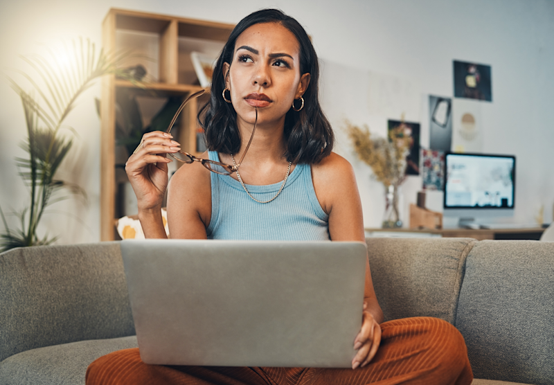 A woman sitting on a couch with a laptop.