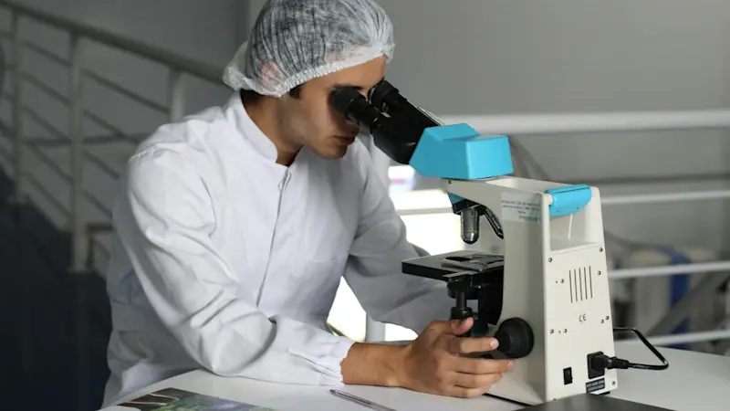 A scientist sat at his desk conducting research with a machine.