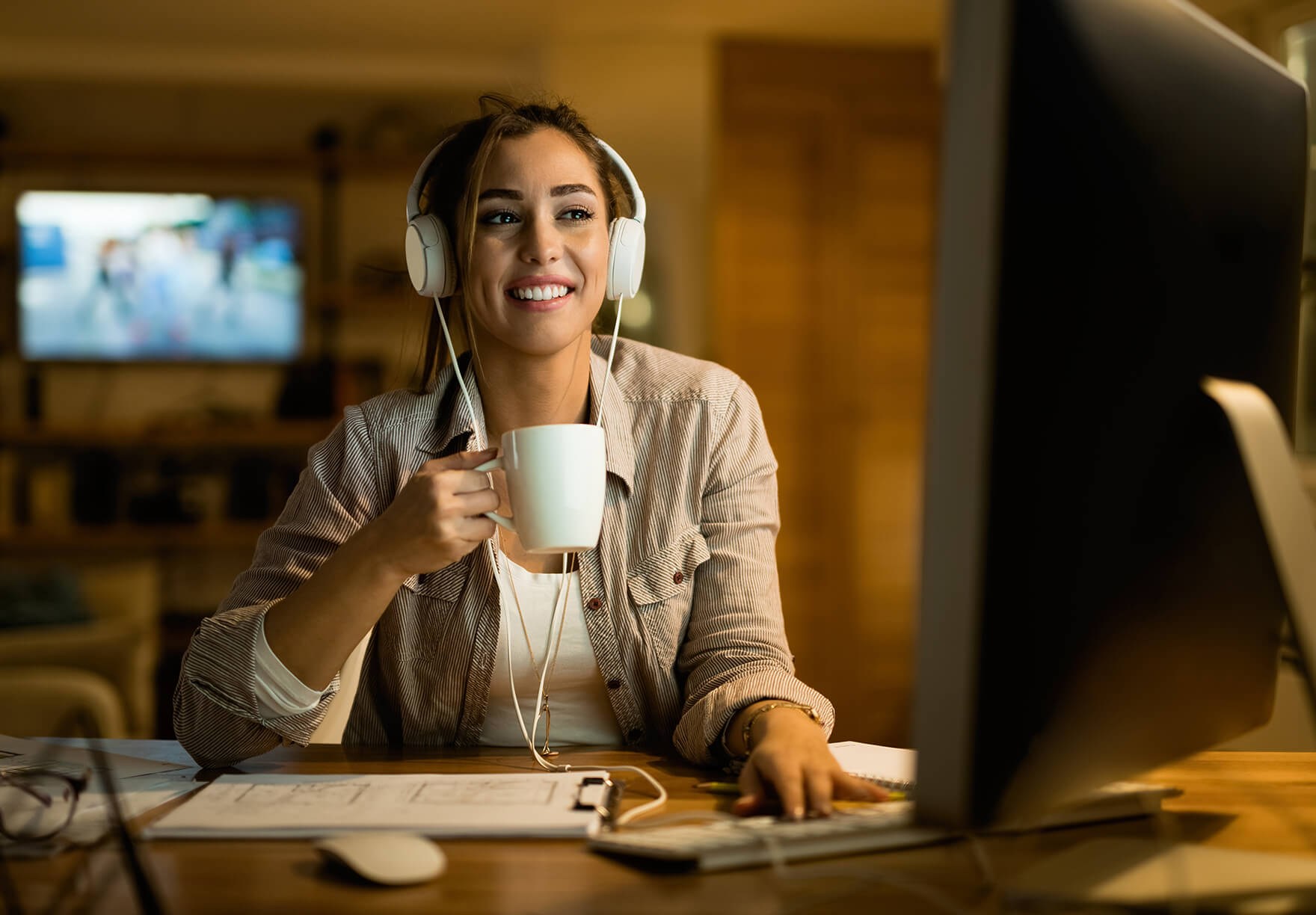 A woman with headphones enjoying coffee on a video call