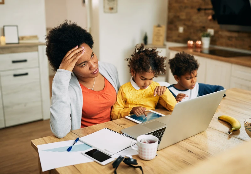 woman working with two children playing nearby