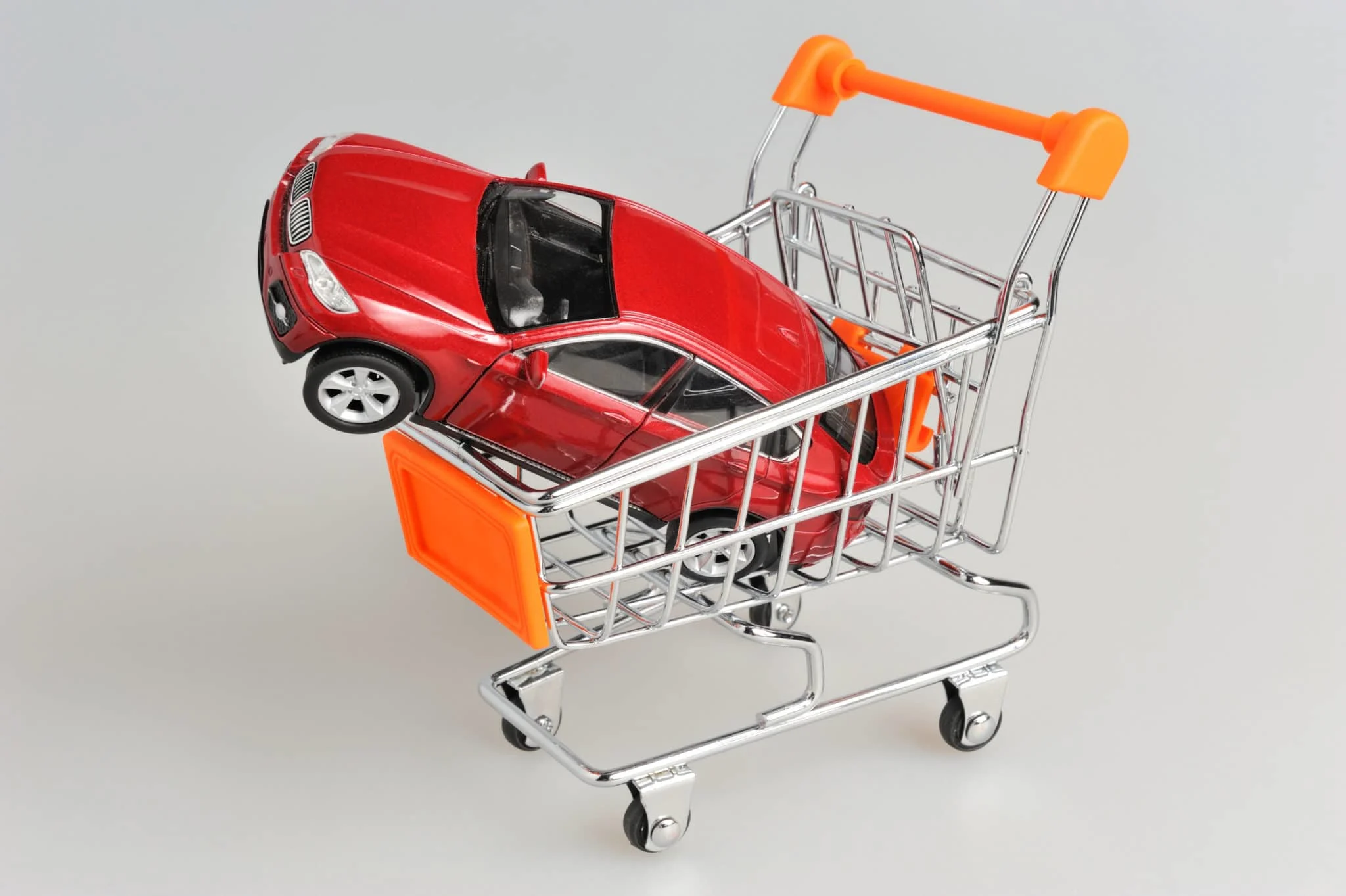 Toy car in shopping cart on gray