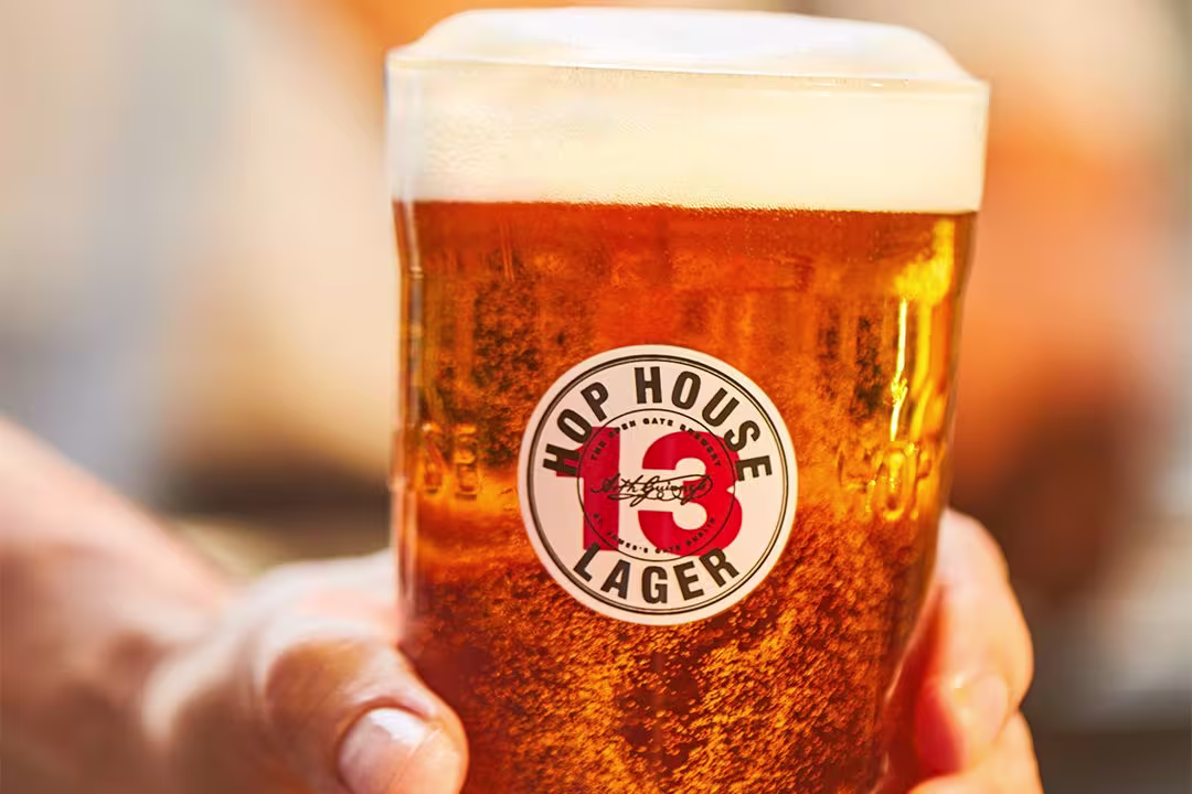 someone holding a glass of beer with a red and white number thirteen on it