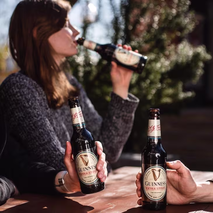 there are two women sitting at a table drinking beer