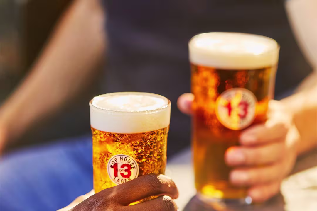 there are two people sitting at a table with two beers