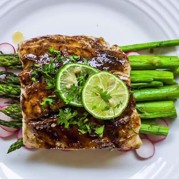 there is a plate of food with asparagus and a lime slice