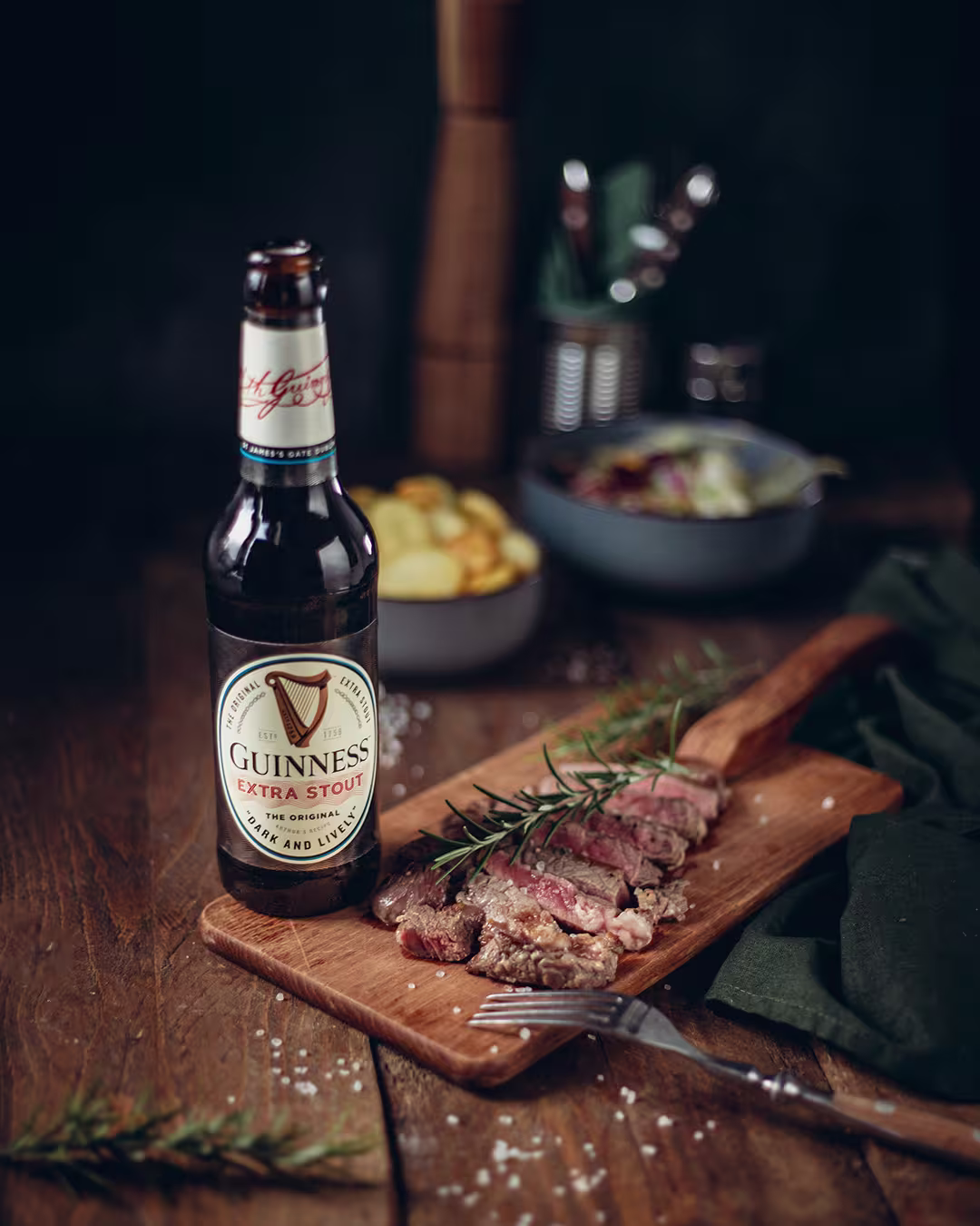 there is a bottle of guinness beer and a steak on a cutting board