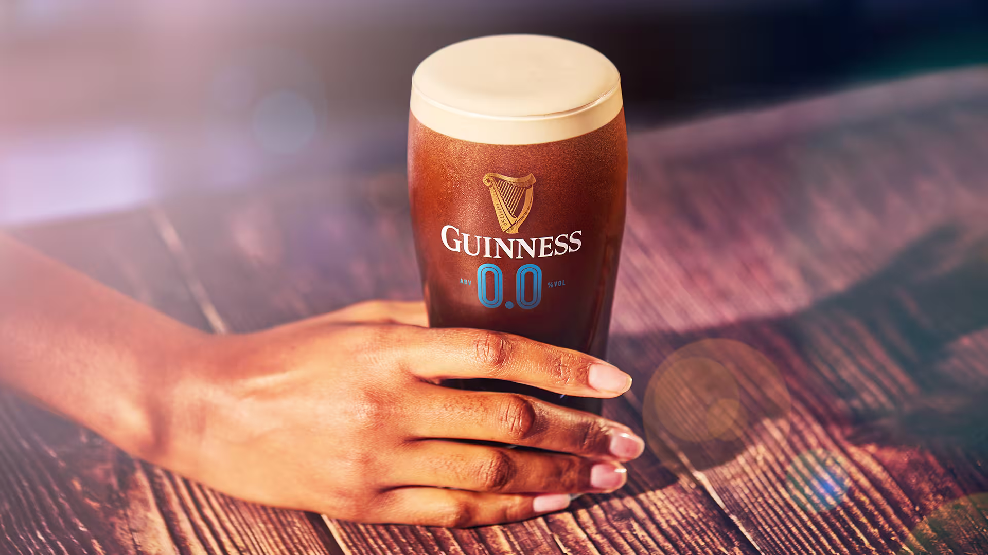someone holding a glass of guinness beer on a table