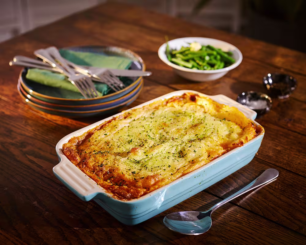 there is a casserole dish with a spoon and a bowl of vegetables