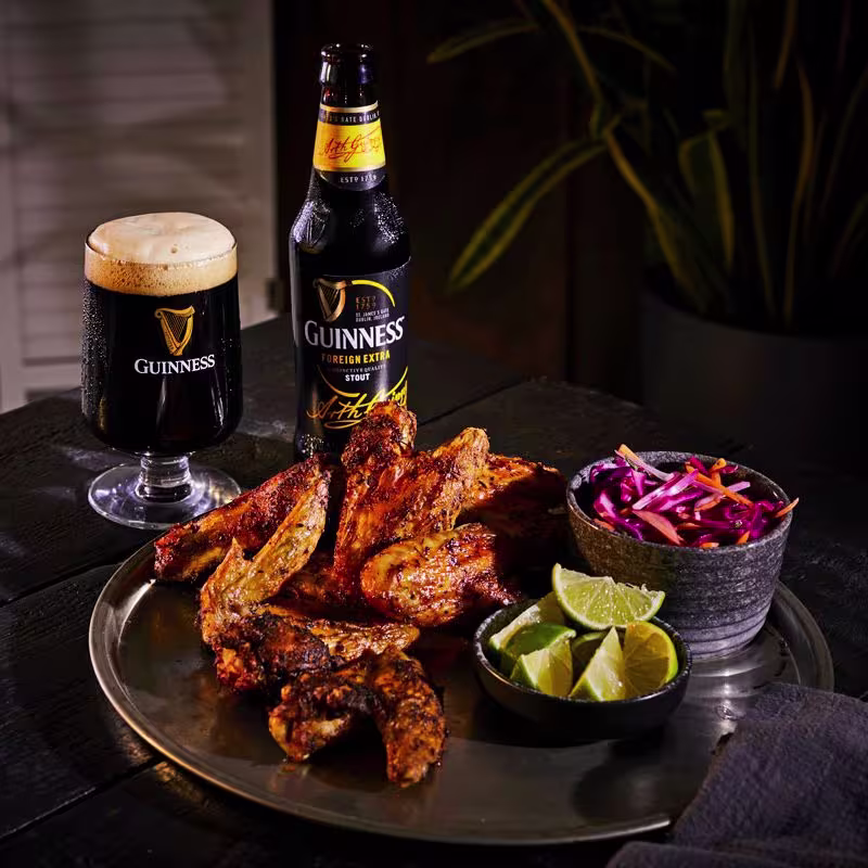there is a plate of ribs and a bowl of coleslaw and a beer