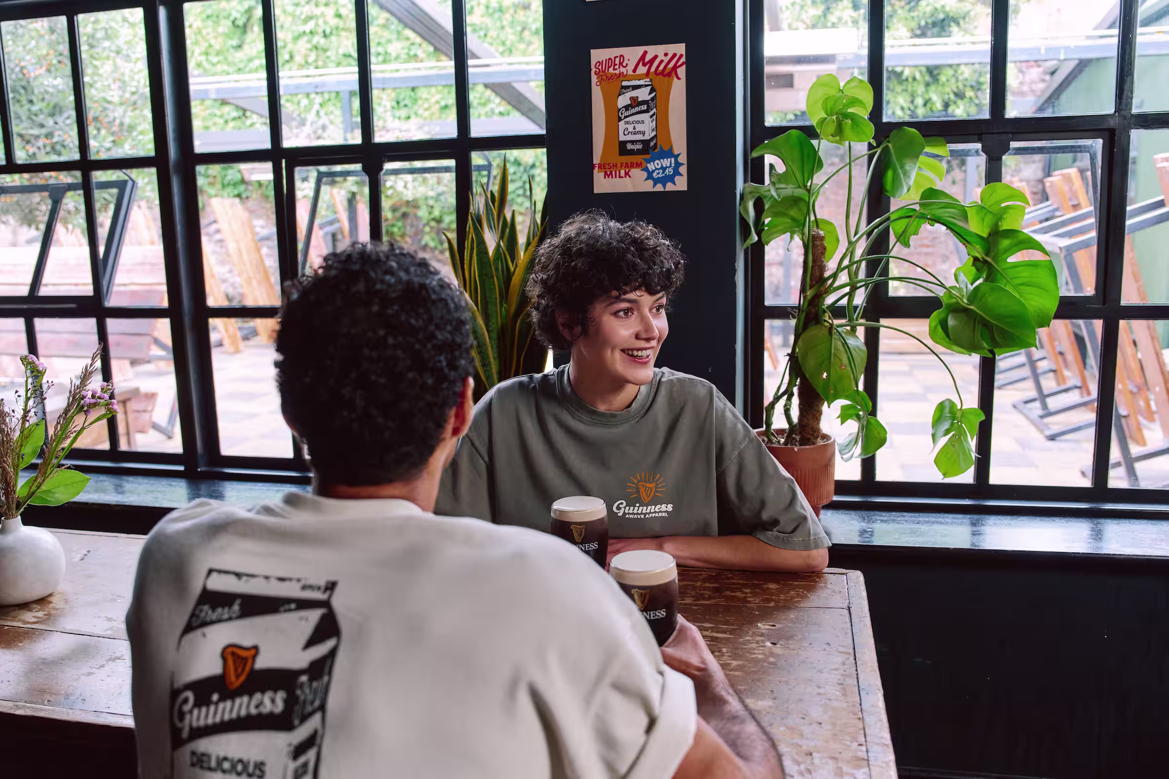 Two people sitting at the table, drinking Guinness and wearing Guinness t-shirts
