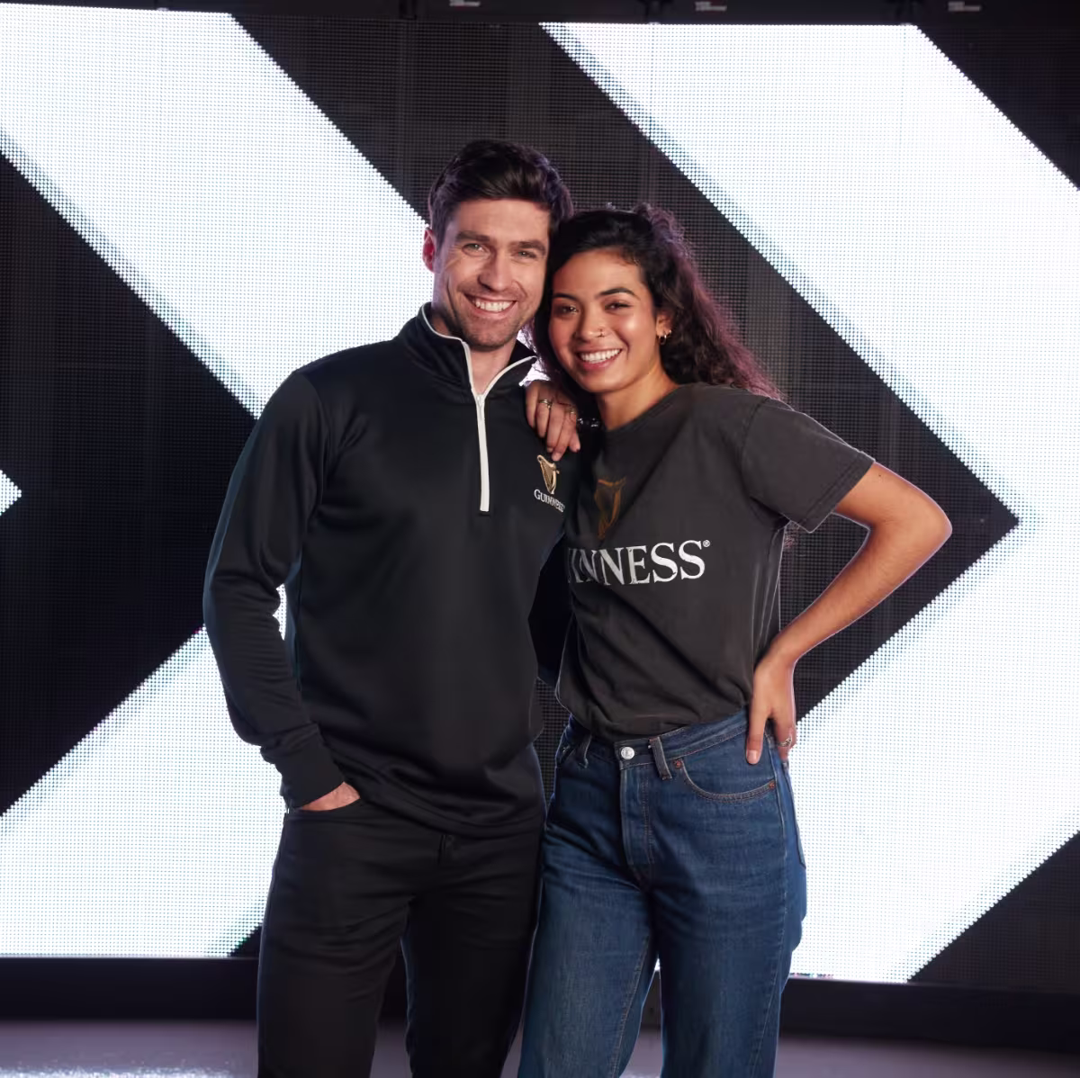 arafed man and woman standing next to each other in front of a large screen