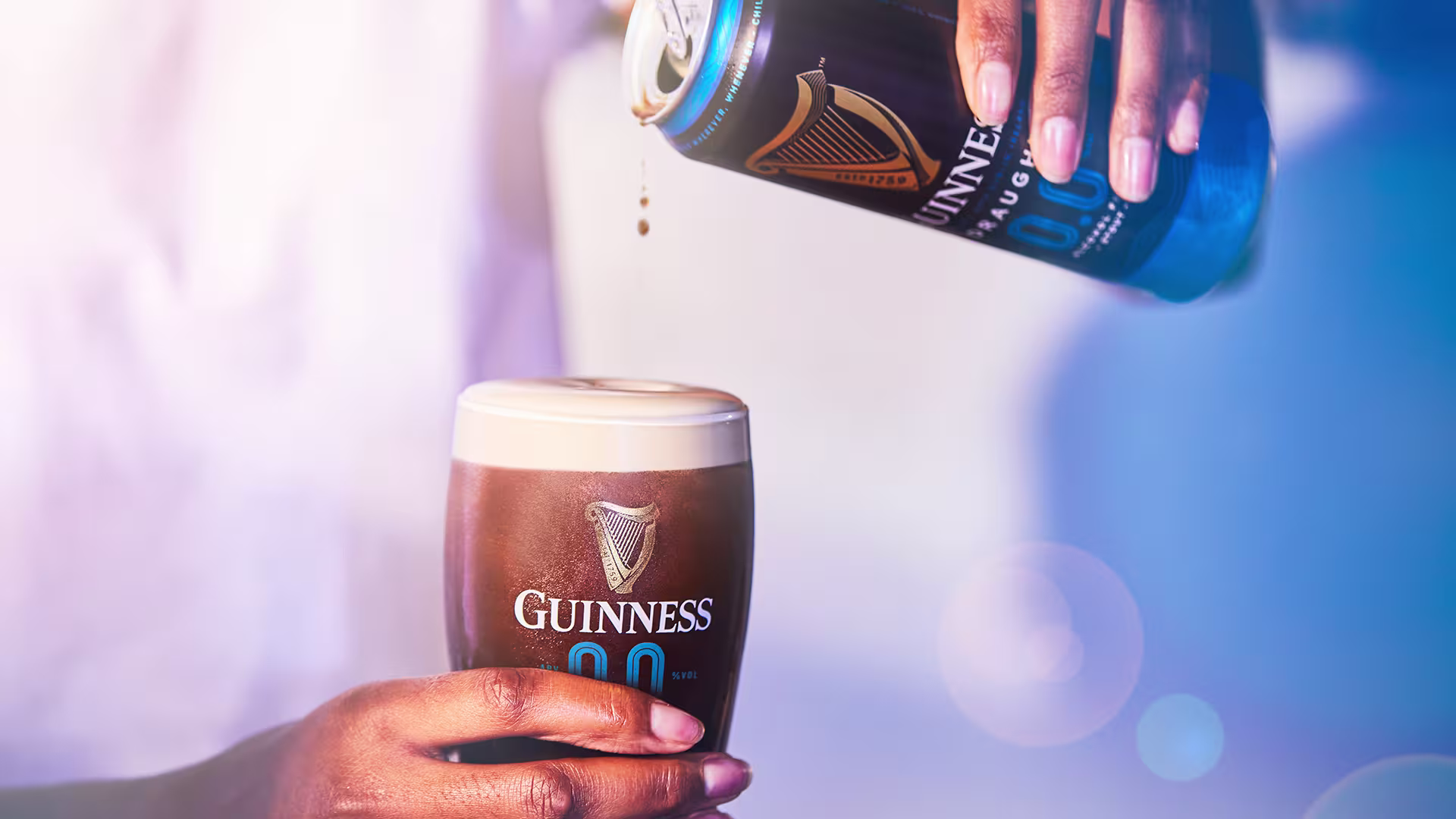 someone pouring a beer into a glass with a bottle in the background