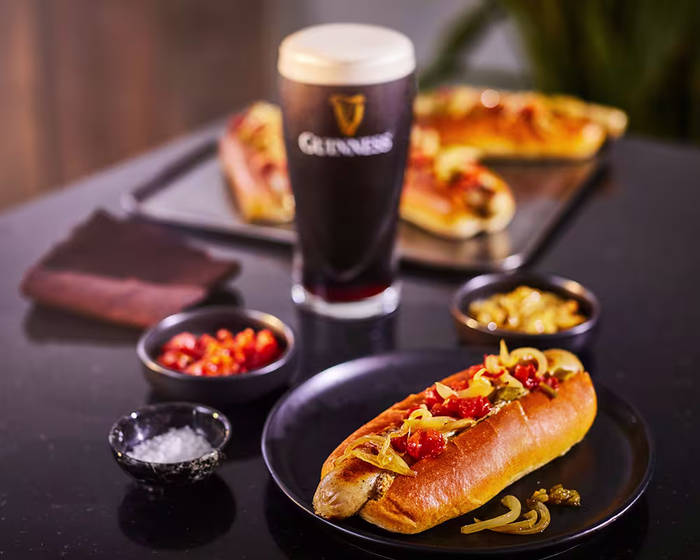 there is a plate with a hot dog and a glass of beer