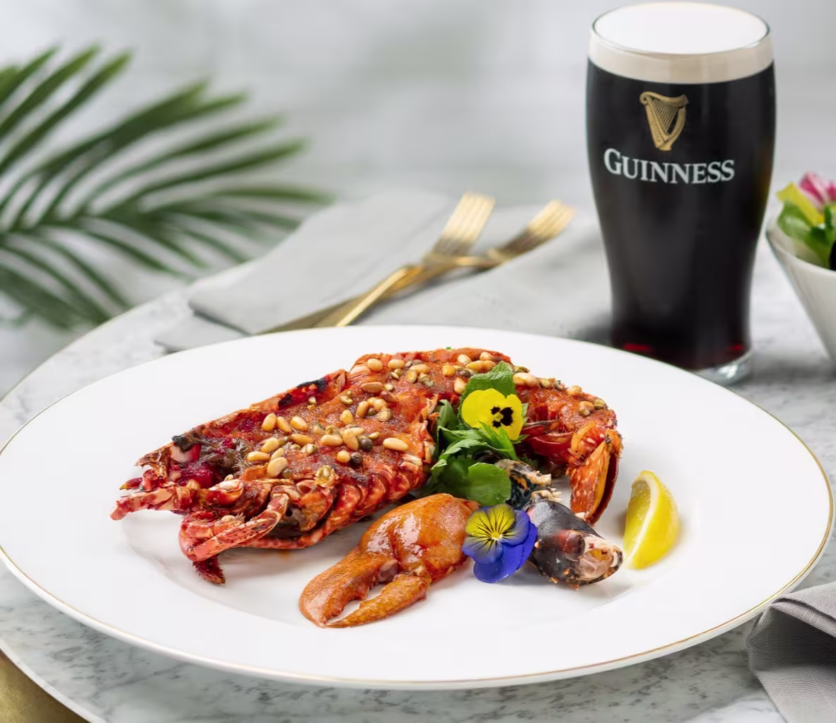 An image of a lobster on a plate and glass of Guinness next to it