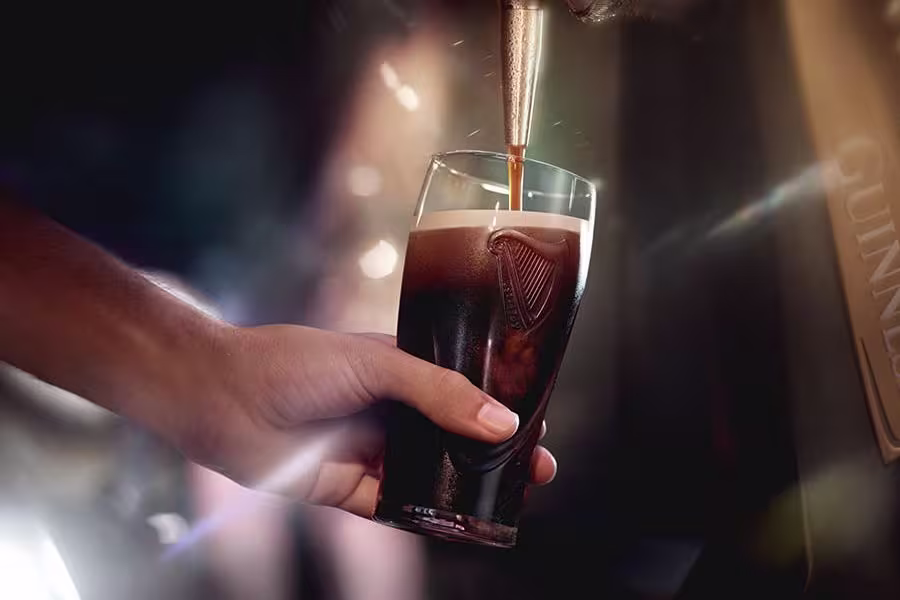 someone is pouring a beer into a glass in a bar