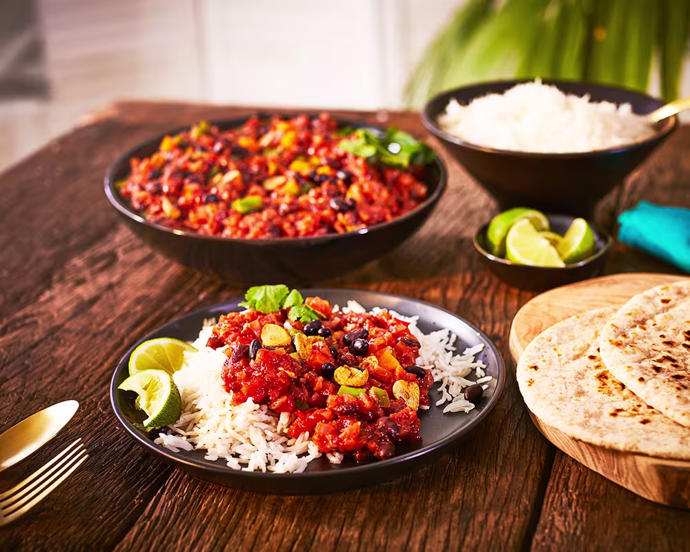 there are two plates of food on a table with a bowl of rice