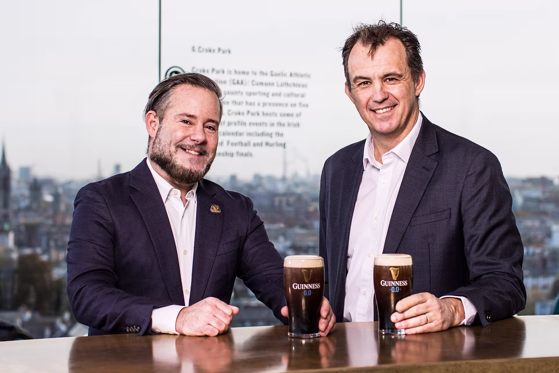 two men in suits are holding up two glasses of beer