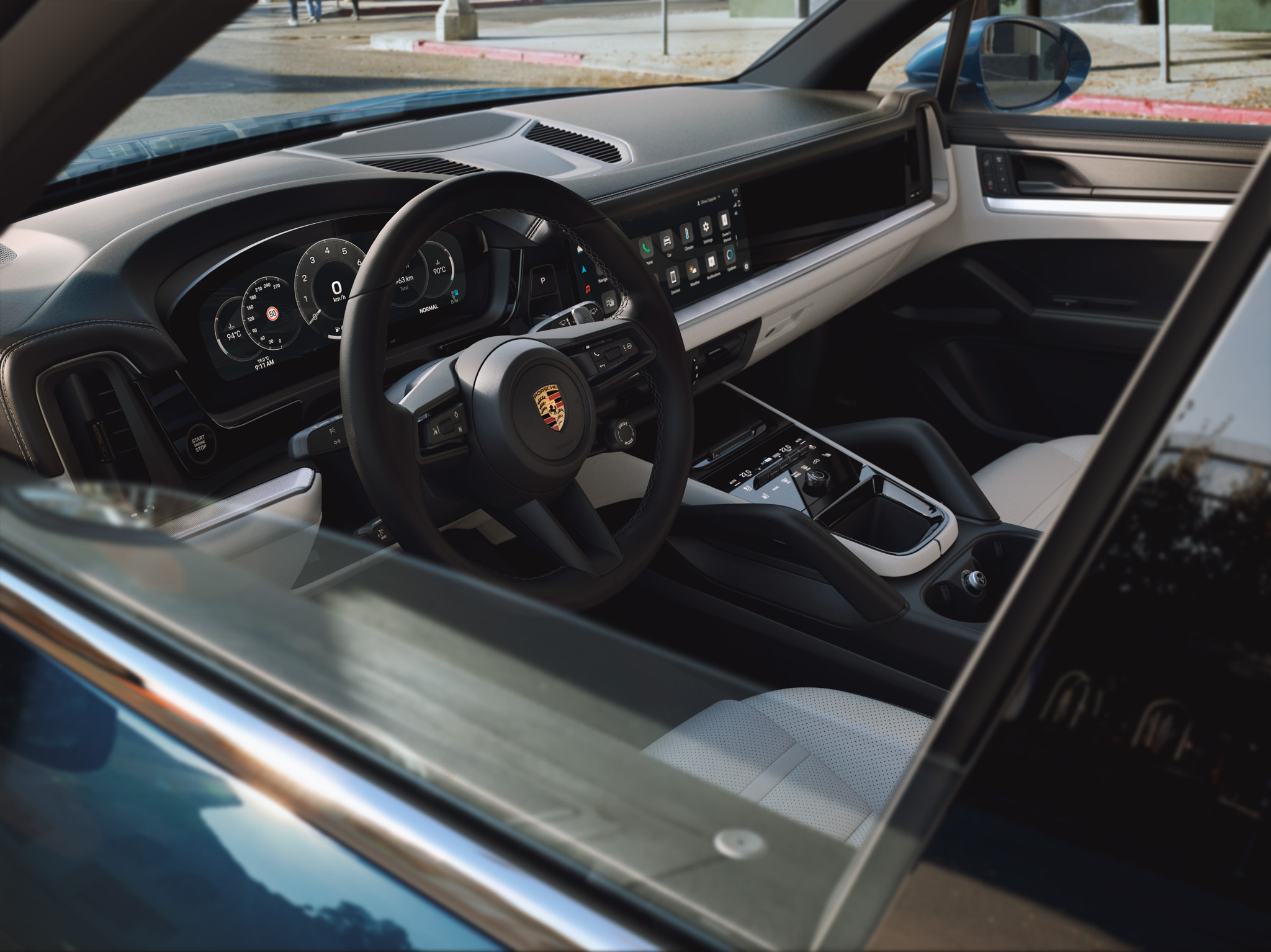 Showing the interior of a cayenne, focusing on the front row. The wheel is displayed and also the display with some apps.
