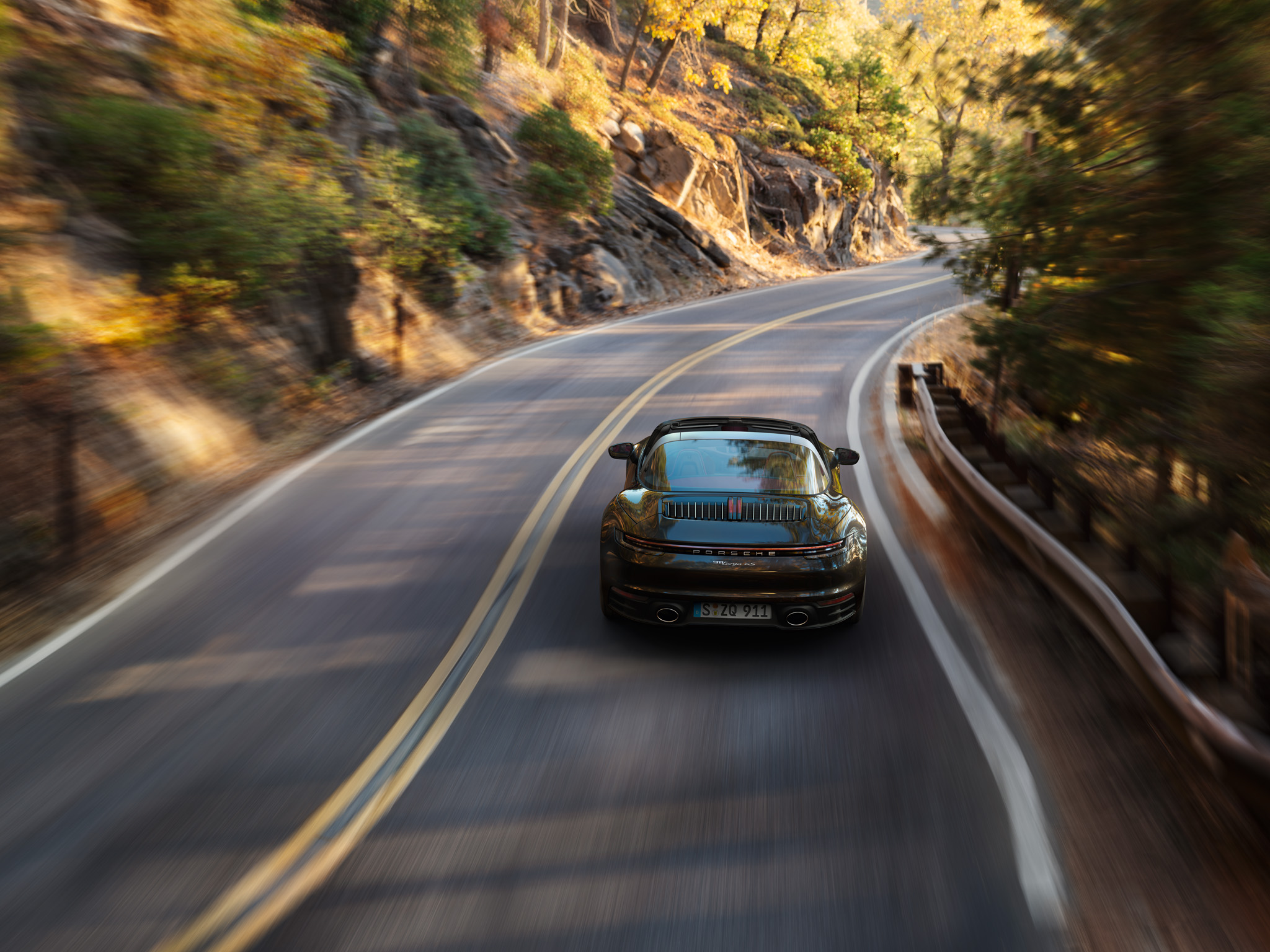 A black Porsche 911 diving along a street