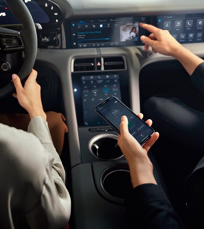 A woman driving a Porsche Cayenne while the man next to her holds his smartphone