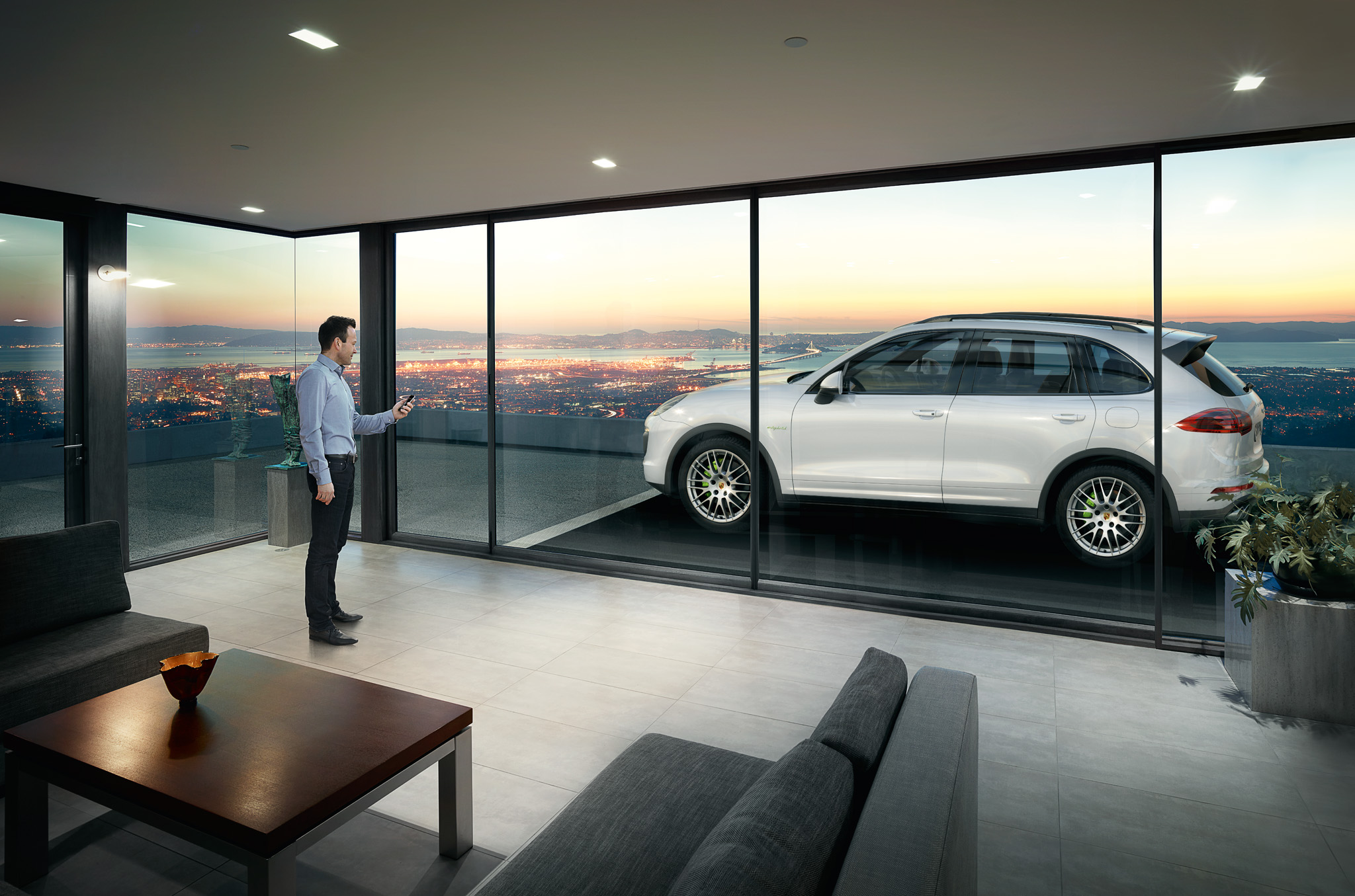 A man holding his smartphone in front of a white Porsche Cayenne
