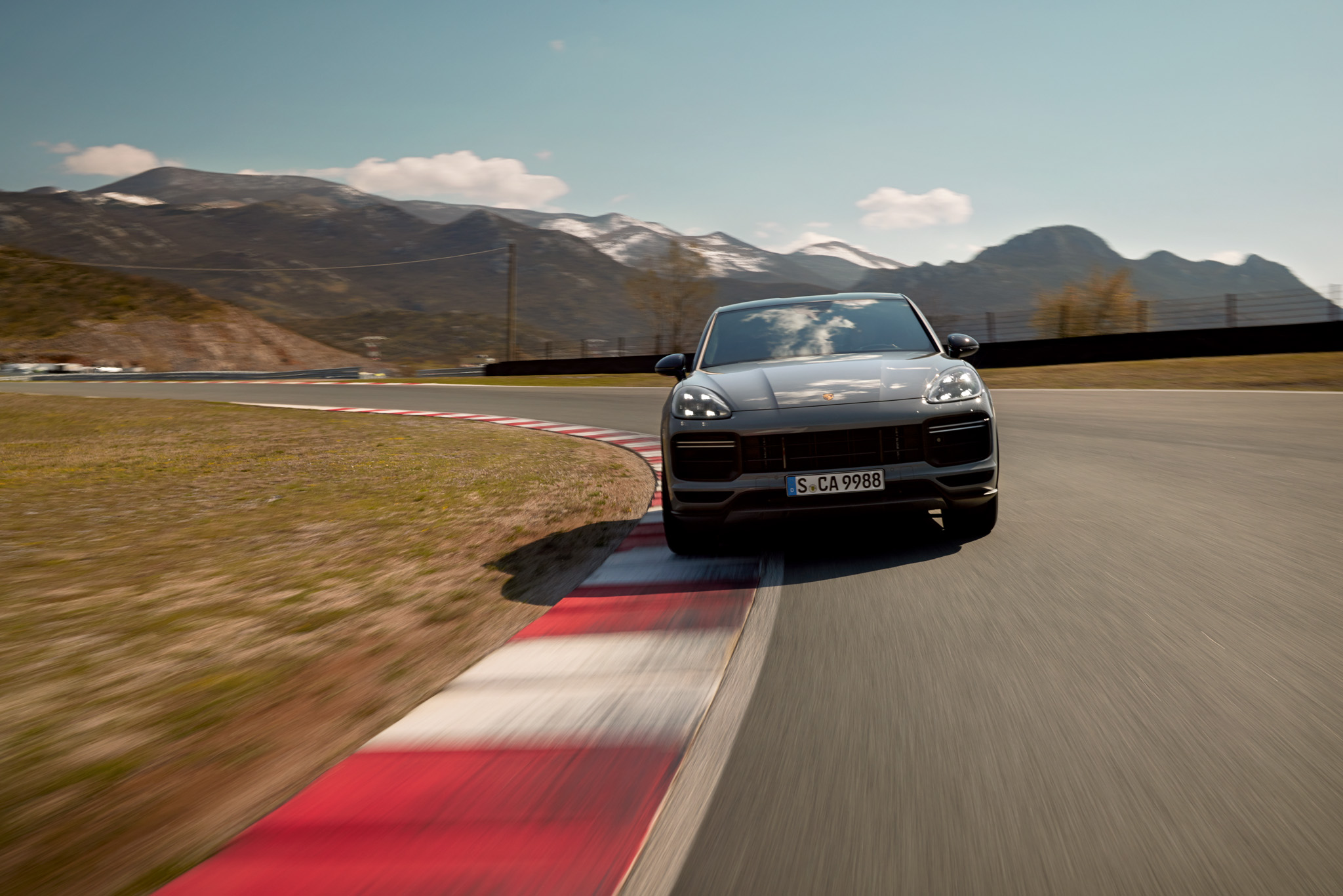 A grey Porsche Cayenne driving on a race track 