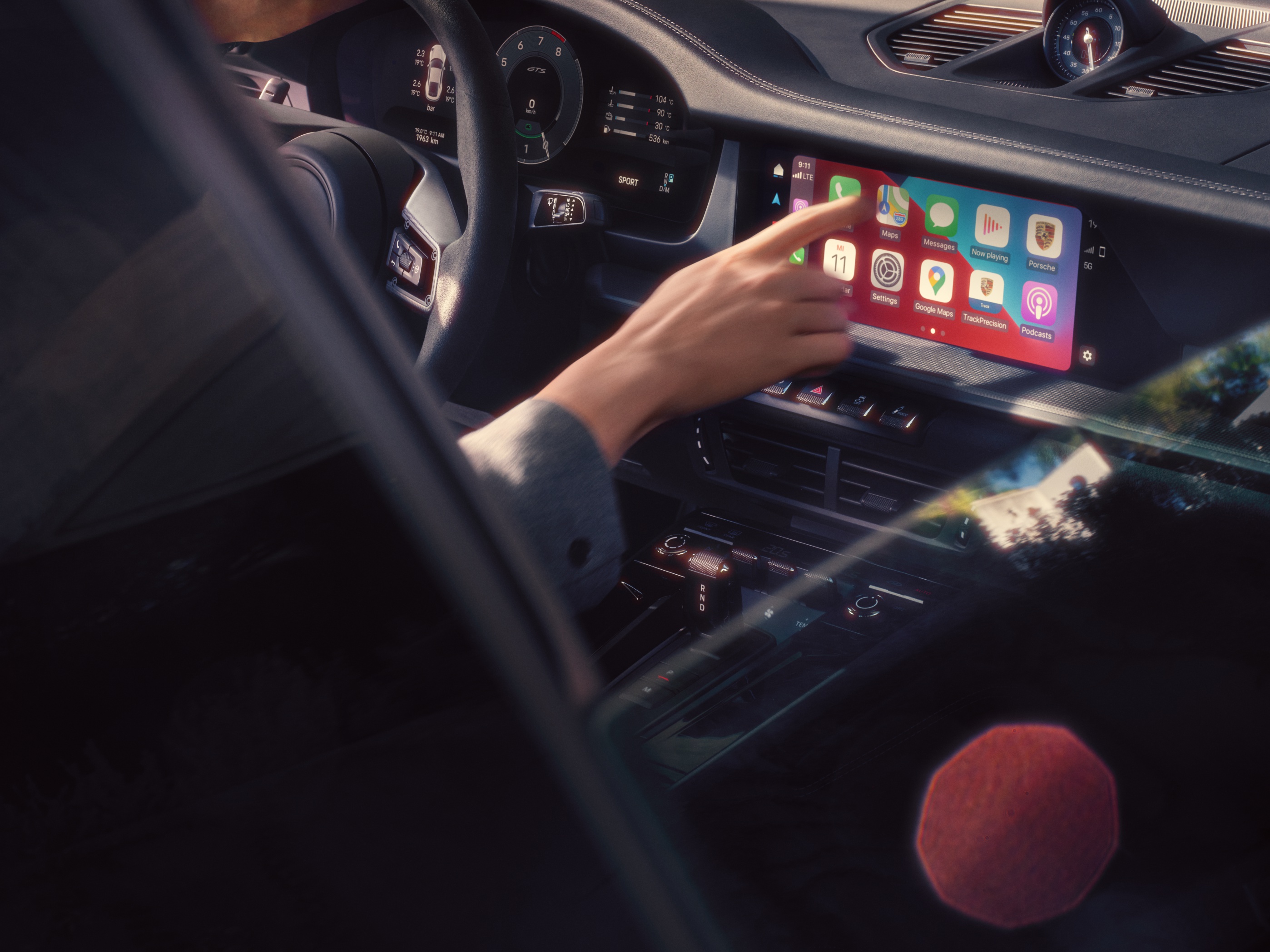 Showing the touch display of a 911 with a woman touching the display and choosing some apps.