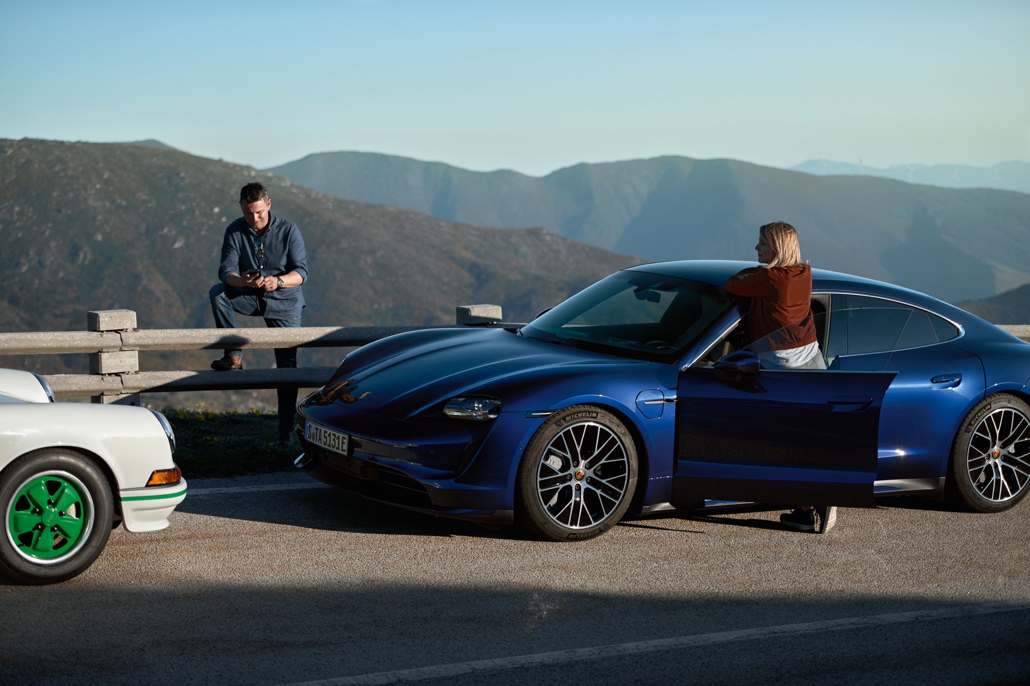 Two people standing in front of two parking Porsches