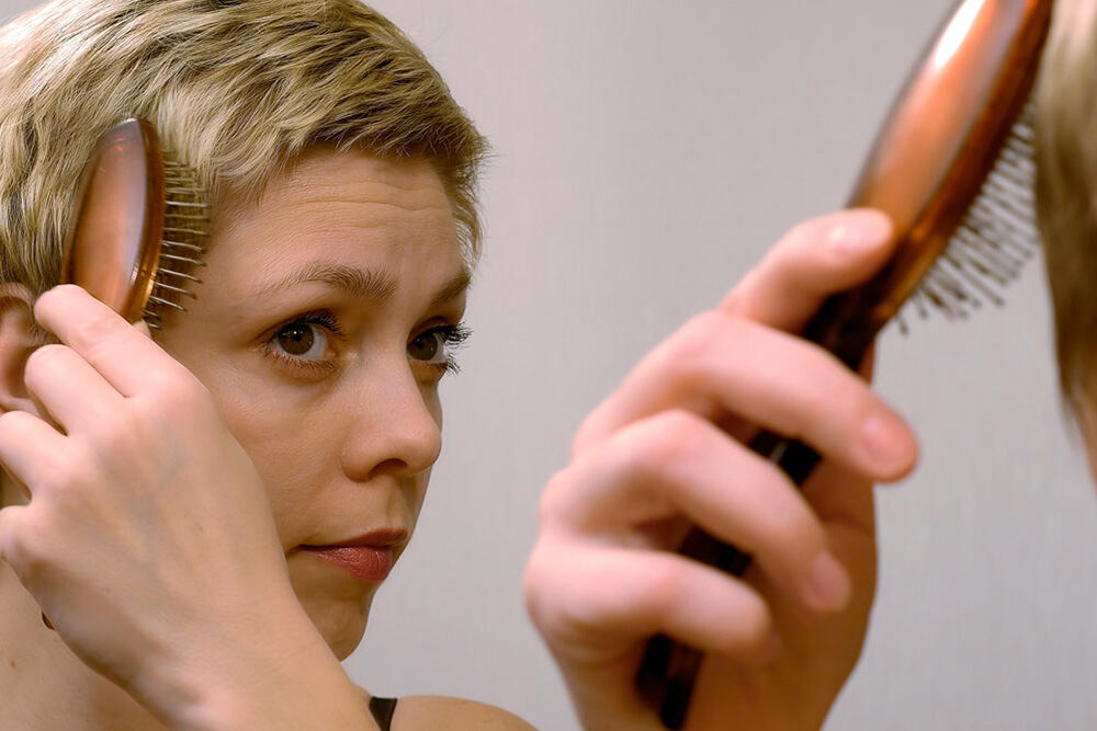 blonde woman brushing her short hair