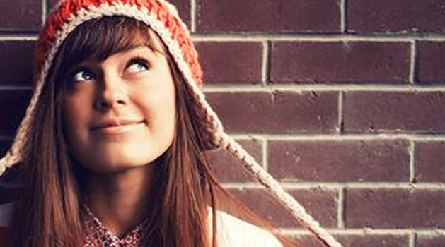 Girl against a wall looking up and smiling